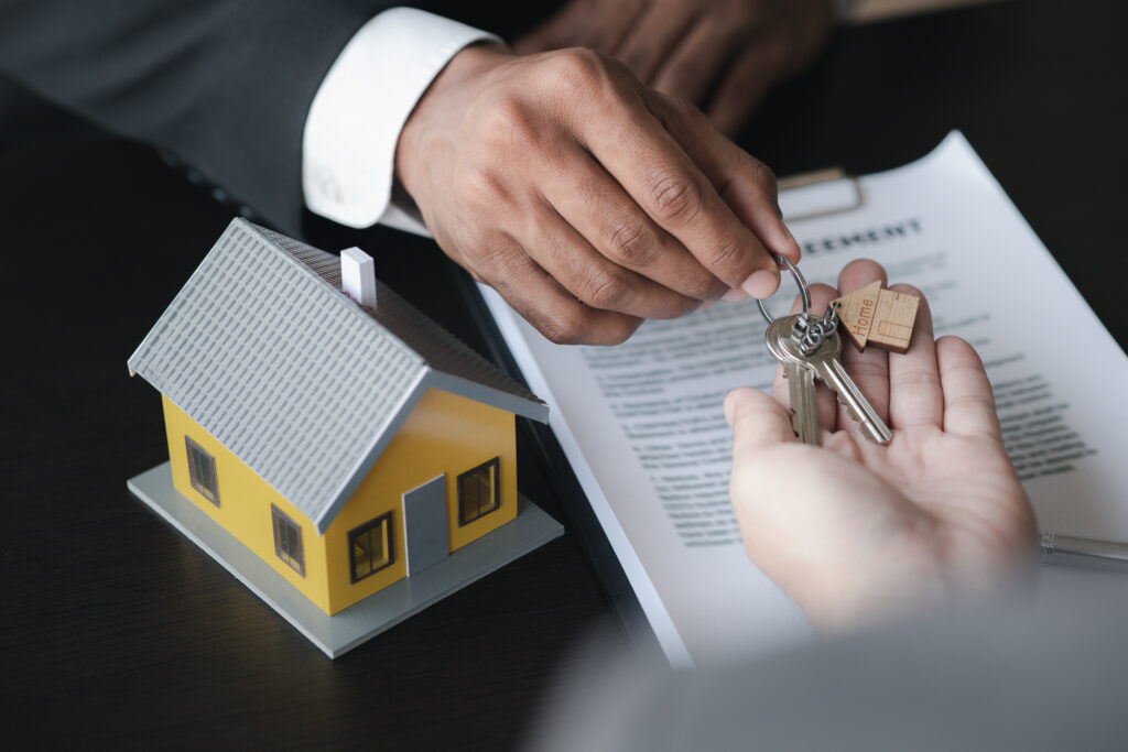 A home rental company employee is handing the house keys to a customer who has agreed to sign a rent