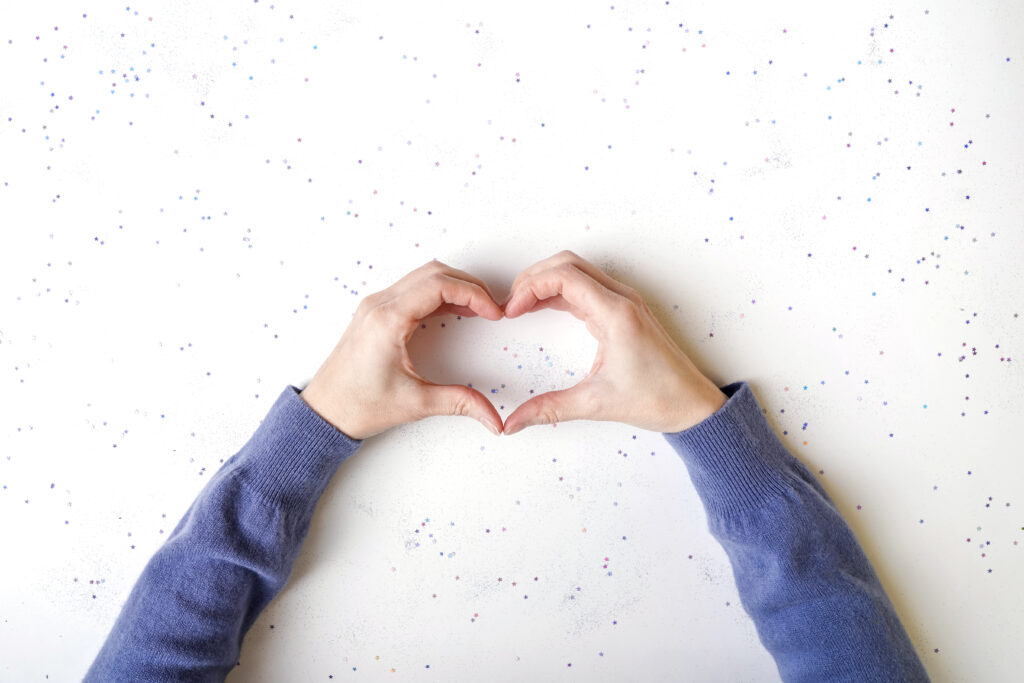 Female hands making sign Heart by fingers.