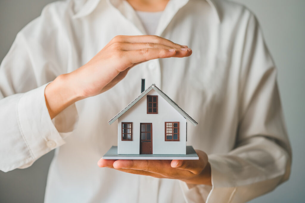 Hand protecting the icon house - the concept of insurance..