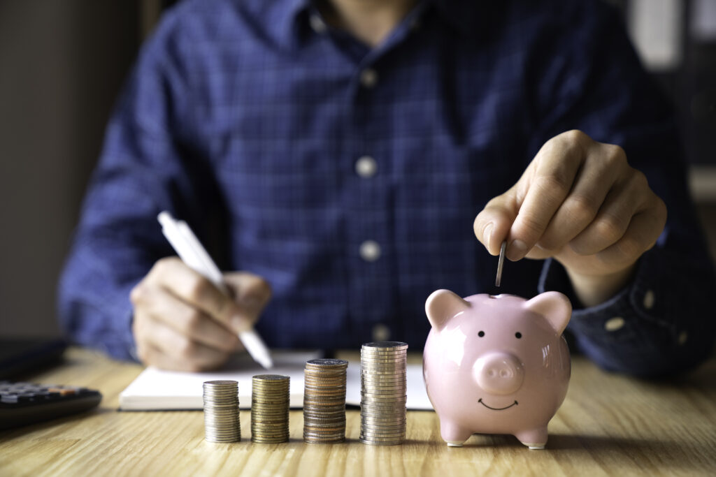 business man holding a coin in a piggy bank to save money Ideas for saving money, taxes, retirement
